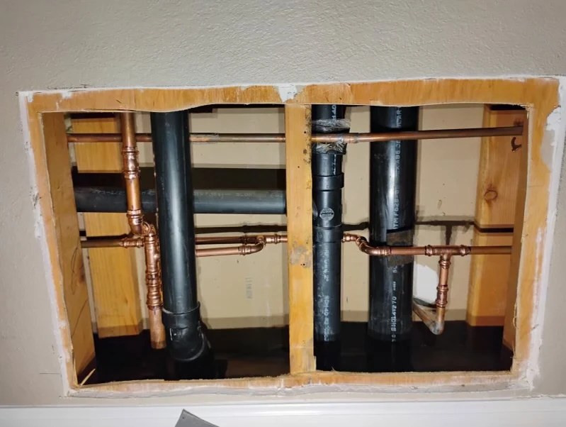 Copper and drain lines run inside an opened wall