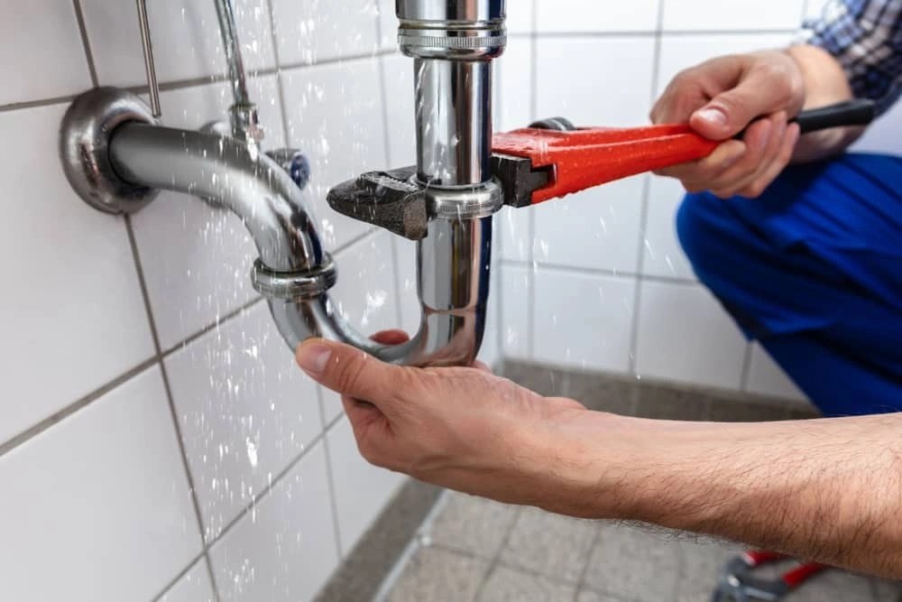 Plumber repairing pipes under a sink