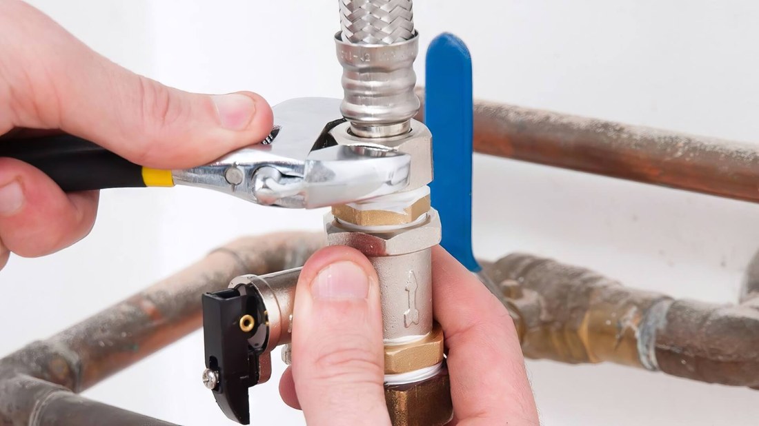 Hands repairing a pipe valve and fittings