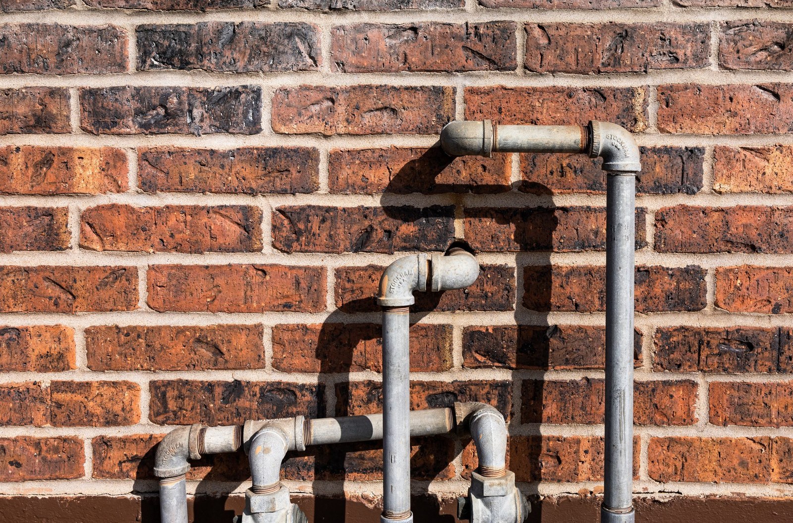 Old galvanized pipes on a brick wall ready for replacement