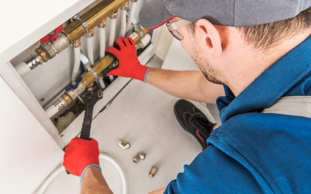 Hands working on copper plumbing pipes and valves