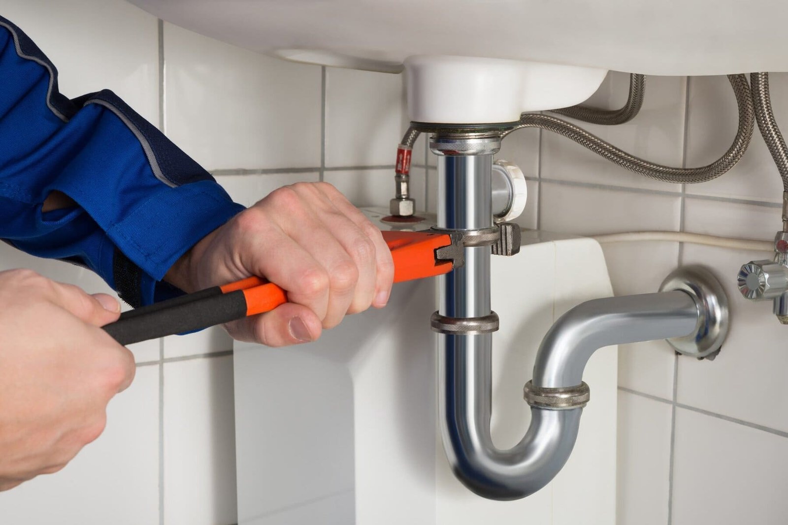 Plumber tightening a sink trap with a wrench